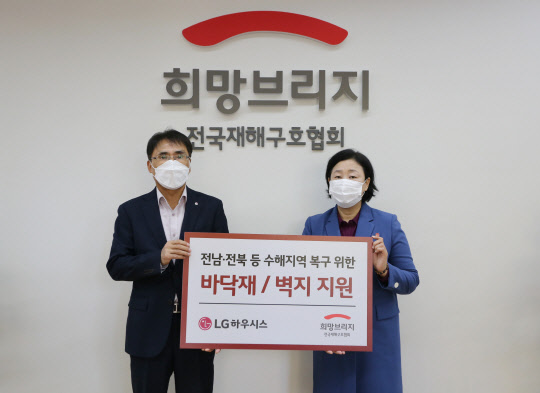 LG하우시스가 지난 8월 발생한 집중호우로 피해를 입은 전남·전북 등 수해지역의 복구를 돕기 위해 바닥재, 벽지 등 자재를 전달했다. 29일 서울 신수로에 있는 희망브리지 전국재해구호협회에서 박귀봉(왼쪽) LG하우시스 장식재사업부장 전무와 김정희 희망브리지 전국재해구호협회 사무총장이 자재 전달식 후 기념촬영을 하고 있다. <LG하우시스 제공>